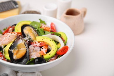 Photo of Bowl of delicious salad with seafood on white table, closeup. Space for text