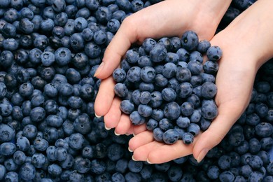 Photo of Woman holding heap of juicy fresh blueberries, top view
