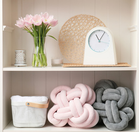 Photo of White shelving unit with flowers and different decorative stuff