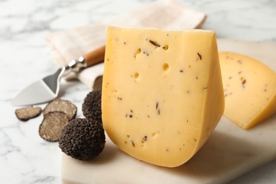 Delicious cheese and fresh black truffles on white marble table, closeup