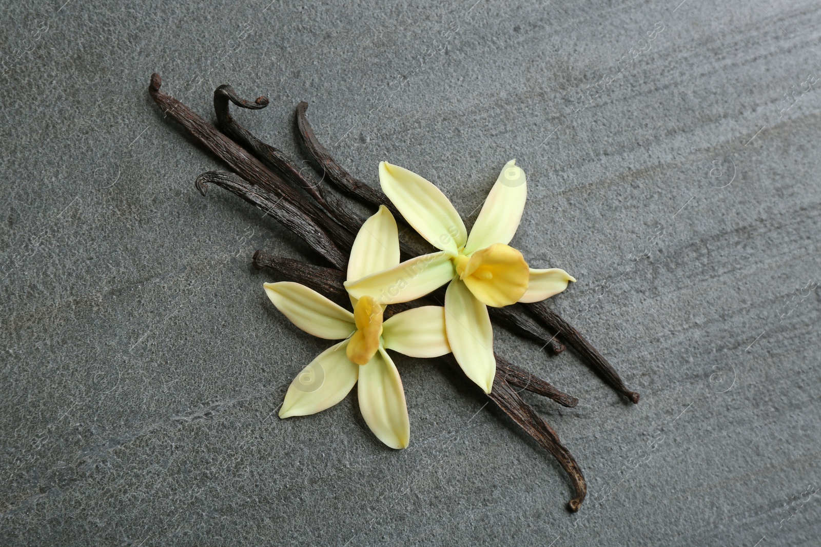 Photo of Flat lay composition with vanilla sticks and flowers on grey background