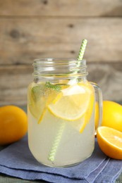 Photo of Cool freshly made lemonade in mason jar on table