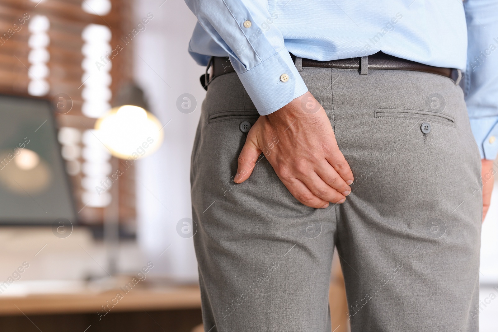 Photo of Man suffering from hemorrhoid in office, closeup