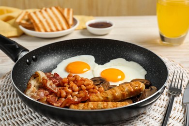 Photo of Frying pan with cooked traditional English breakfast on white table, closeup