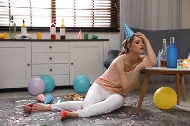 Photo of Sleepy young woman in messy room after party