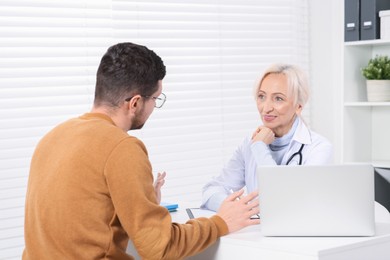 Photo of Doctor consulting patient at white table in clinic