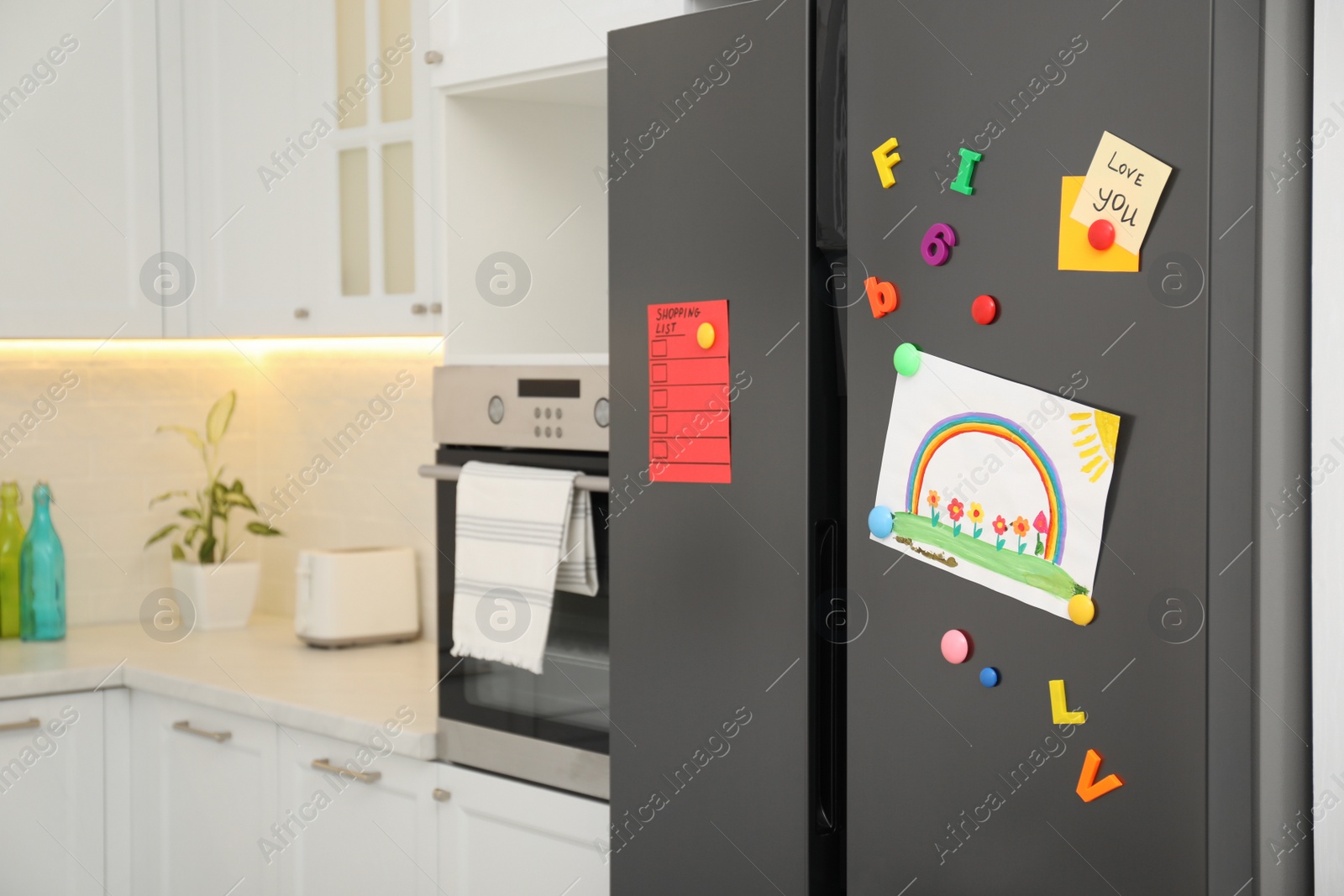 Photo of Modern refrigerator with child's drawing, notes and magnets in kitchen. Space for text