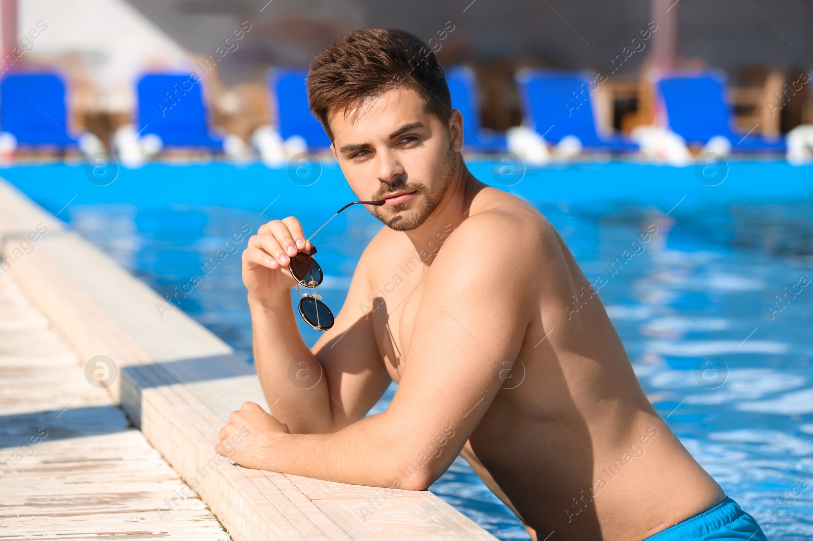 Photo of Handsome young man at swimming pool edge on sunny day