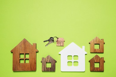 House models and keys on light green background, flat lay. Space for text
