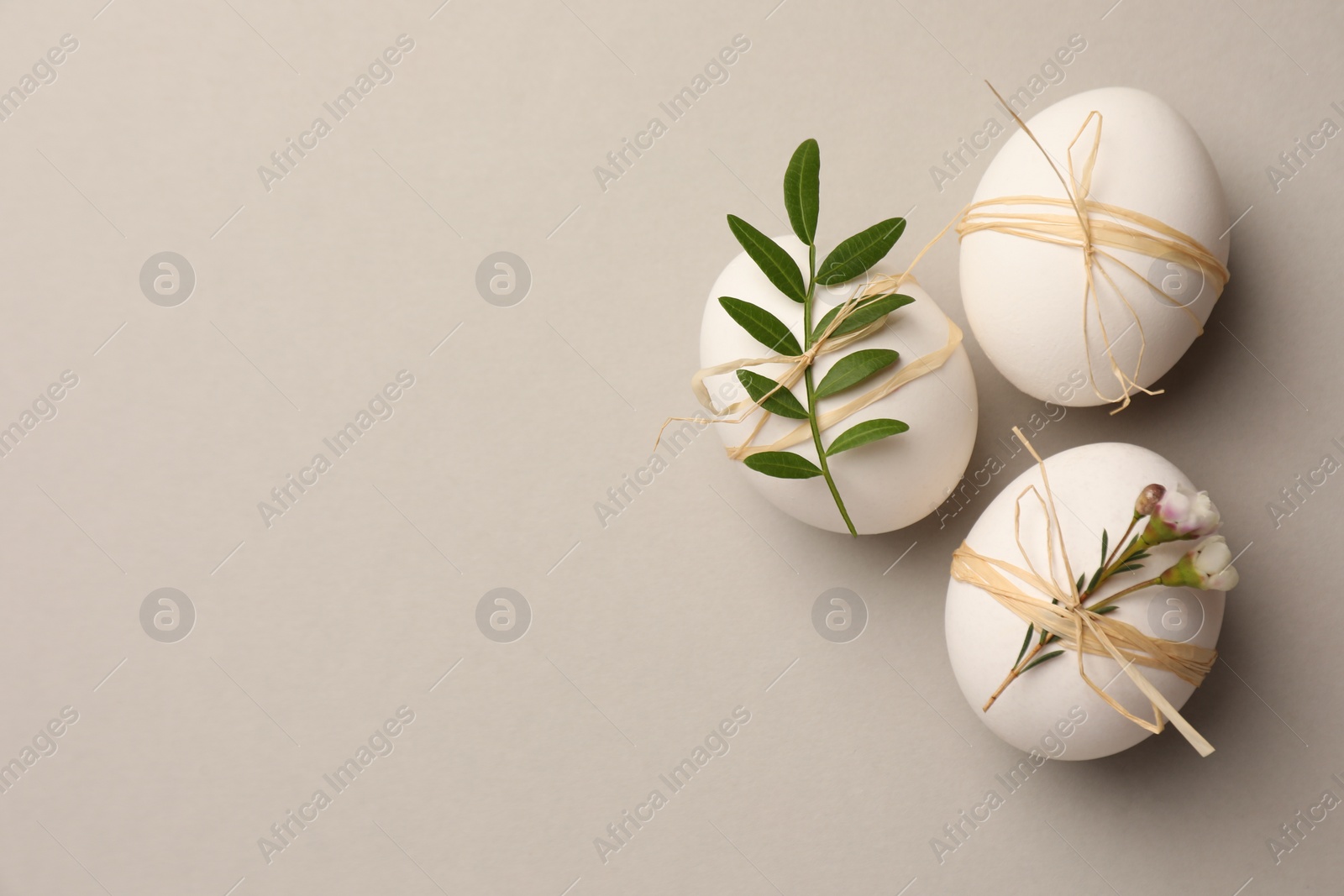 Photo of Festively decorated chicken eggs on light grey background, flat lay with space for text. Happy Easter