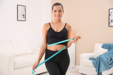 Photo of Slim woman measuring her waist at home. Weight loss