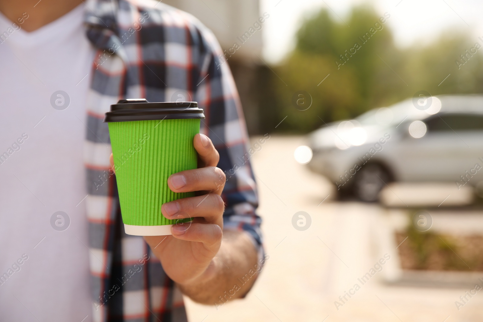 Photo of Man with takeaway coffee cup on city street, closeup. Space for text