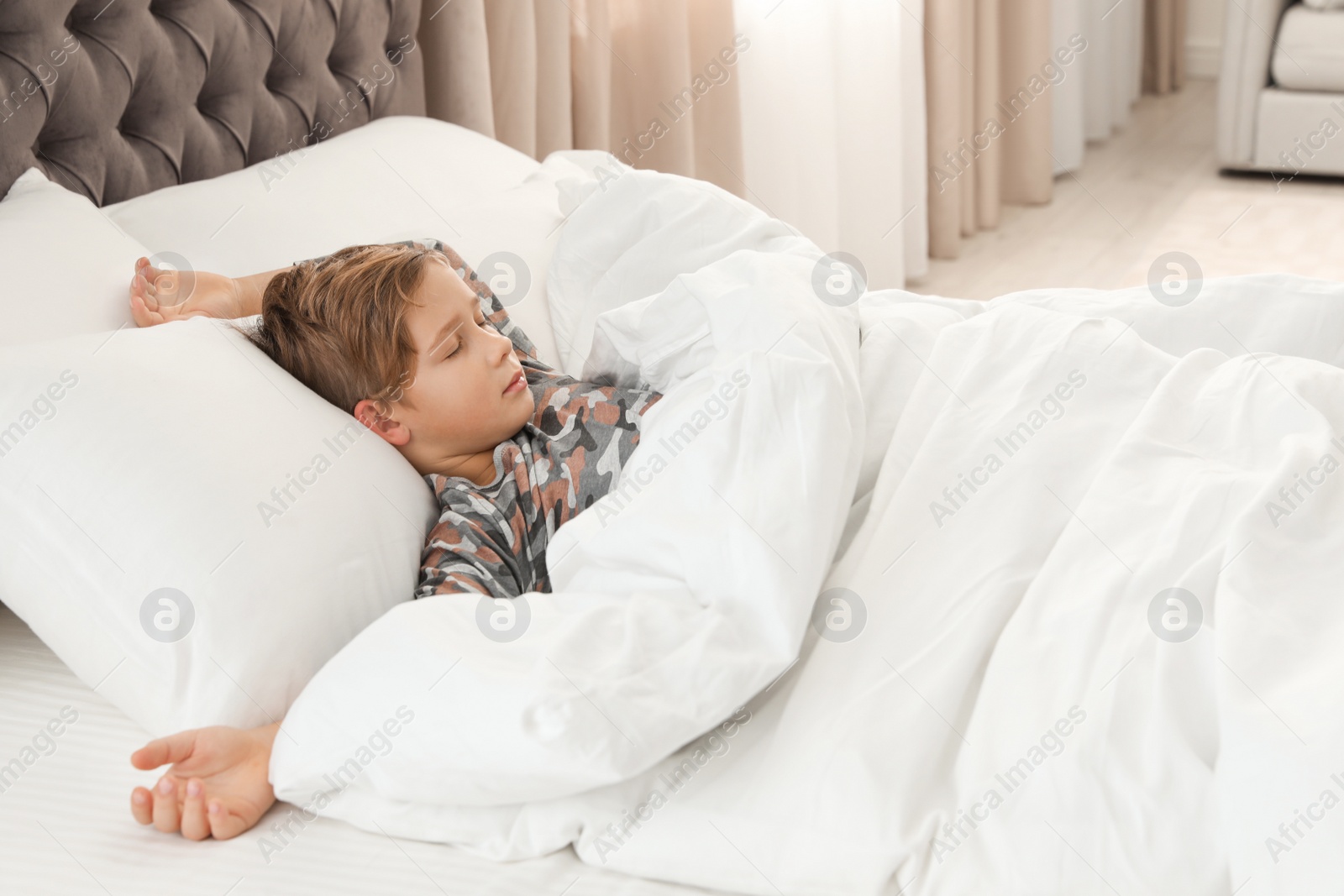 Photo of Cute tired boy sleeping in comfortable bed