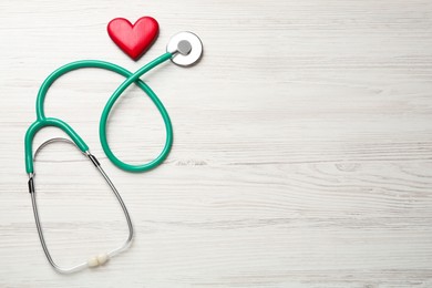 Photo of Stethoscope and red heart on white wooden table, flat lay with space for text. Cardiology concept