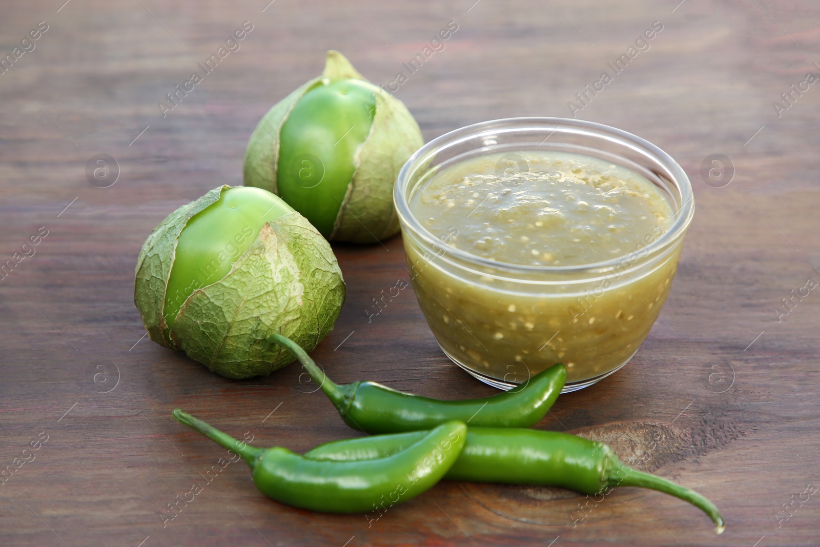 Photo of Tasty salsa sauce and ingredients on wooden table, closeup