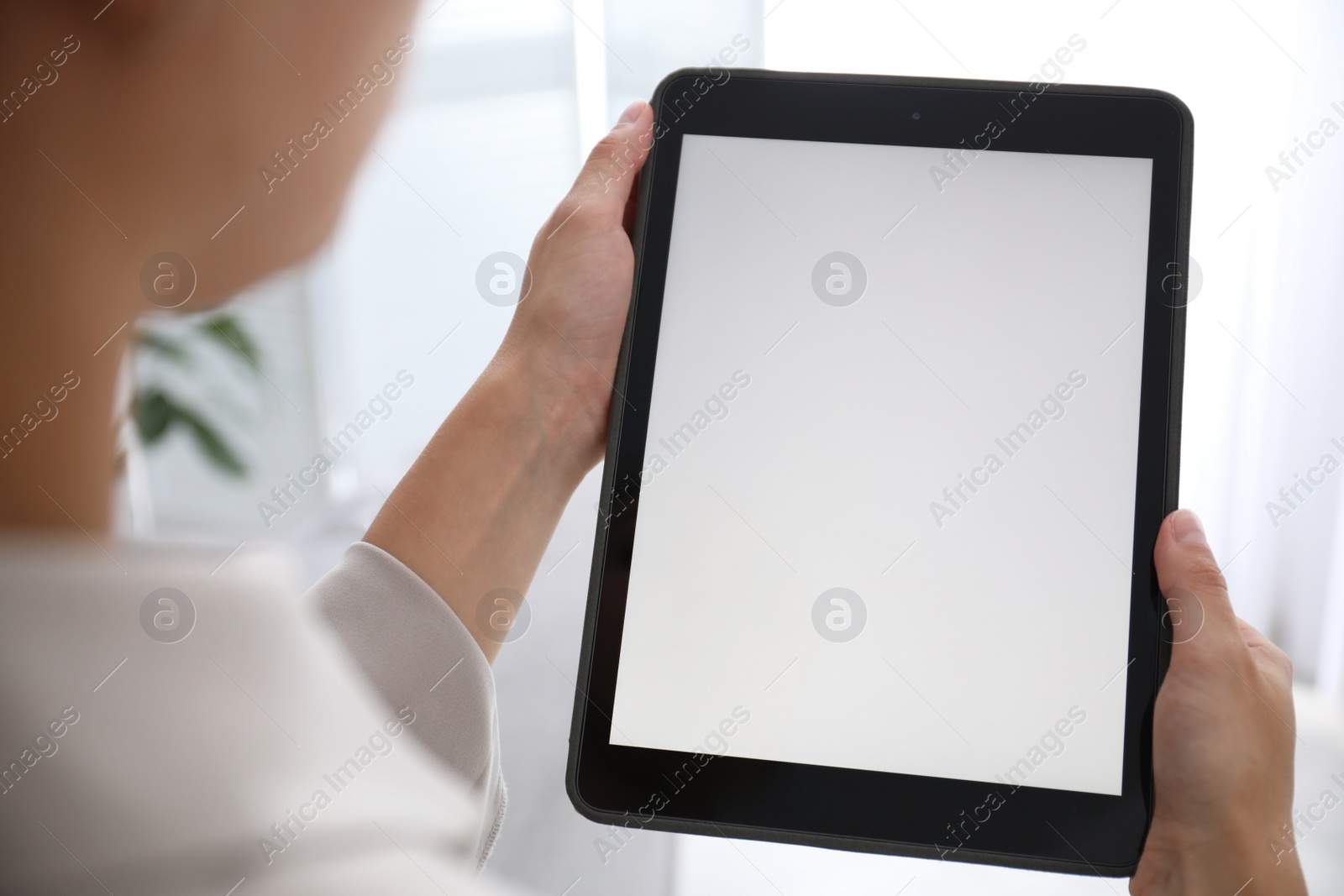 Photo of Woman using modern tablet at home, closeup. Space for design