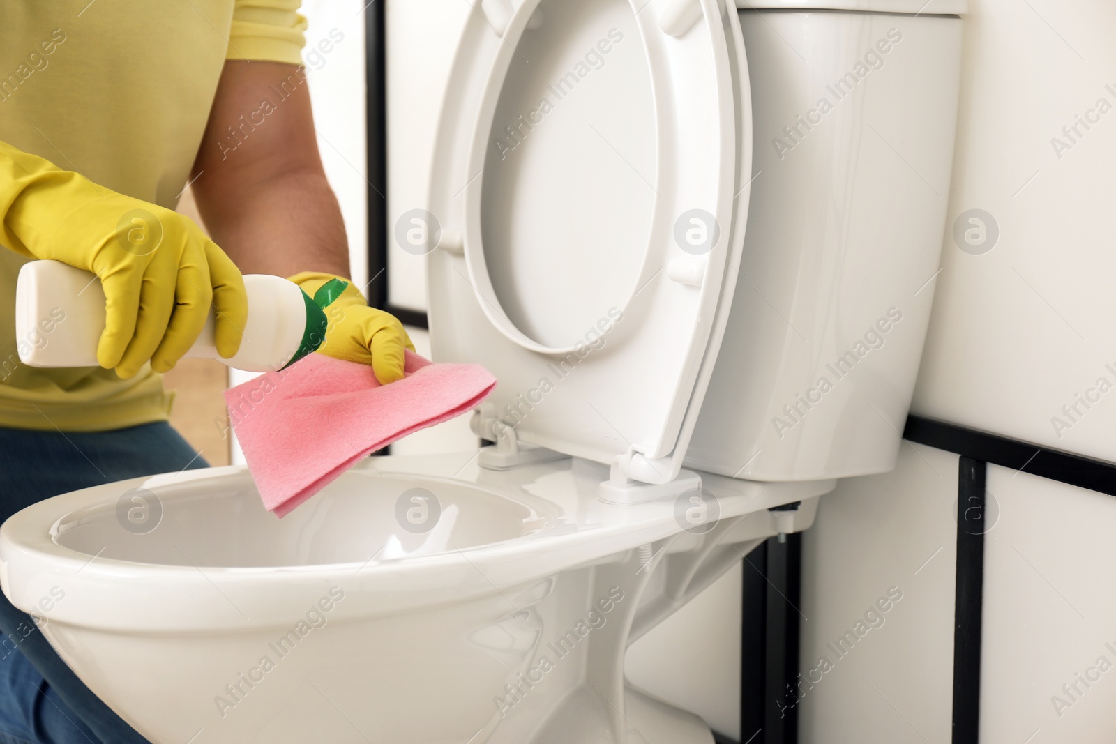 Photo of Man cleaning toilet bowl in bathroom, closeup