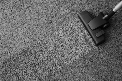 Photo of Modern vacuum cleaner on carpet, top view. Space for text