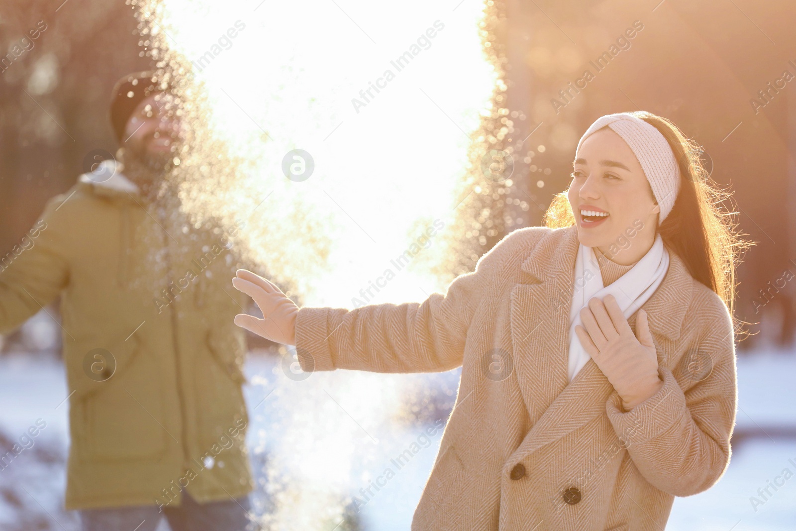 Photo of Happy couple playing snowballs on winter day outdoors