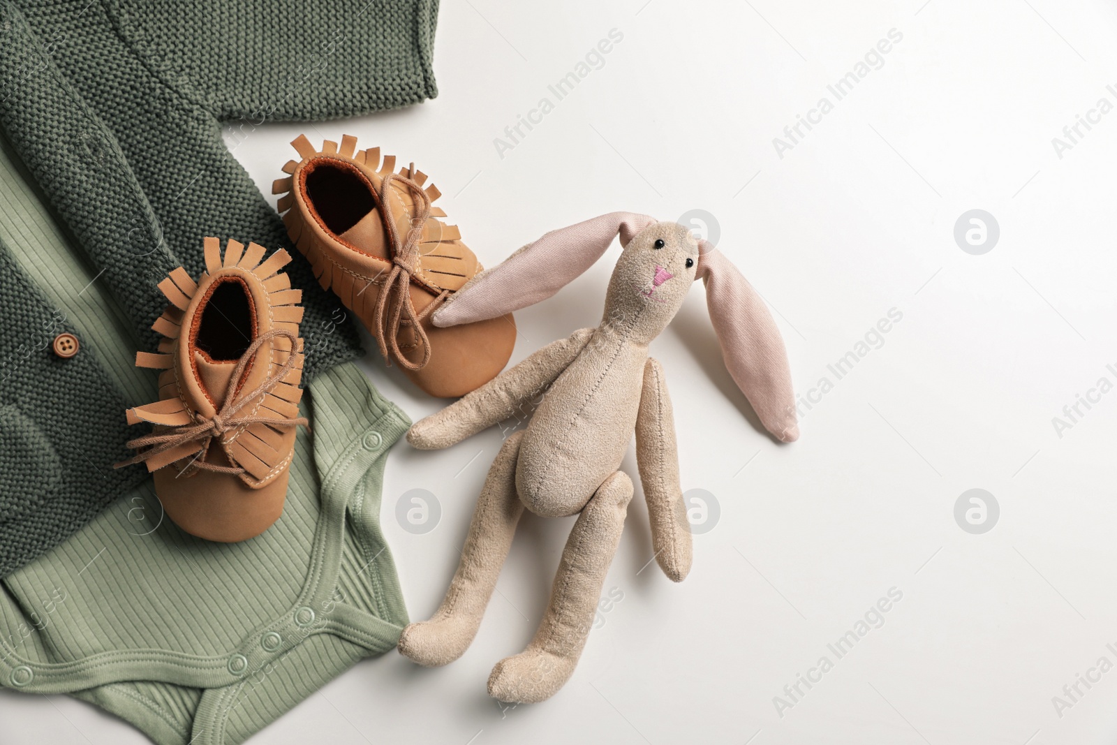 Photo of Baby clothes, shoes and toy bunny on white background, flat lay. Space for text
