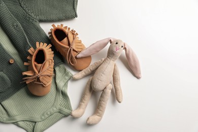 Photo of Baby clothes, shoes and toy bunny on white background, flat lay. Space for text