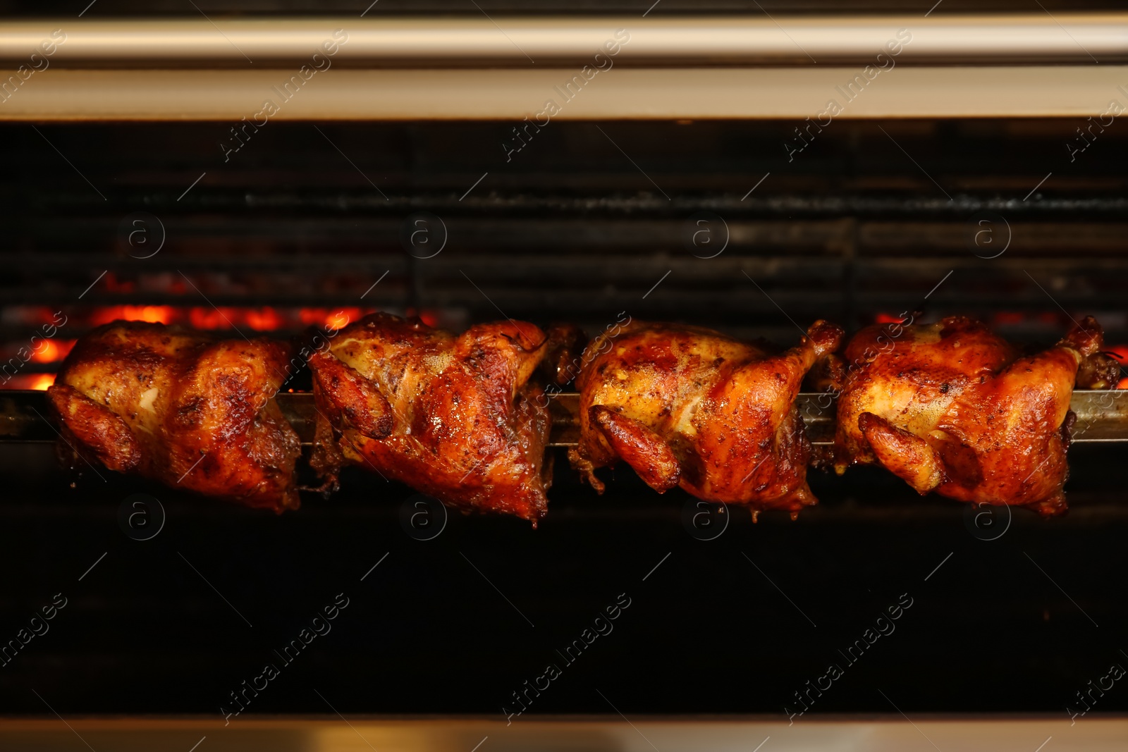 Photo of Grilling whole chickens in rotisserie machine, closeup