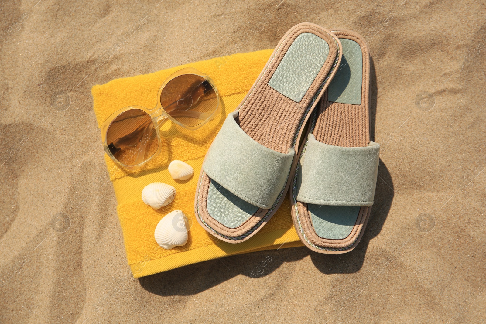 Photo of Beach accessories and seashells on sand, top view