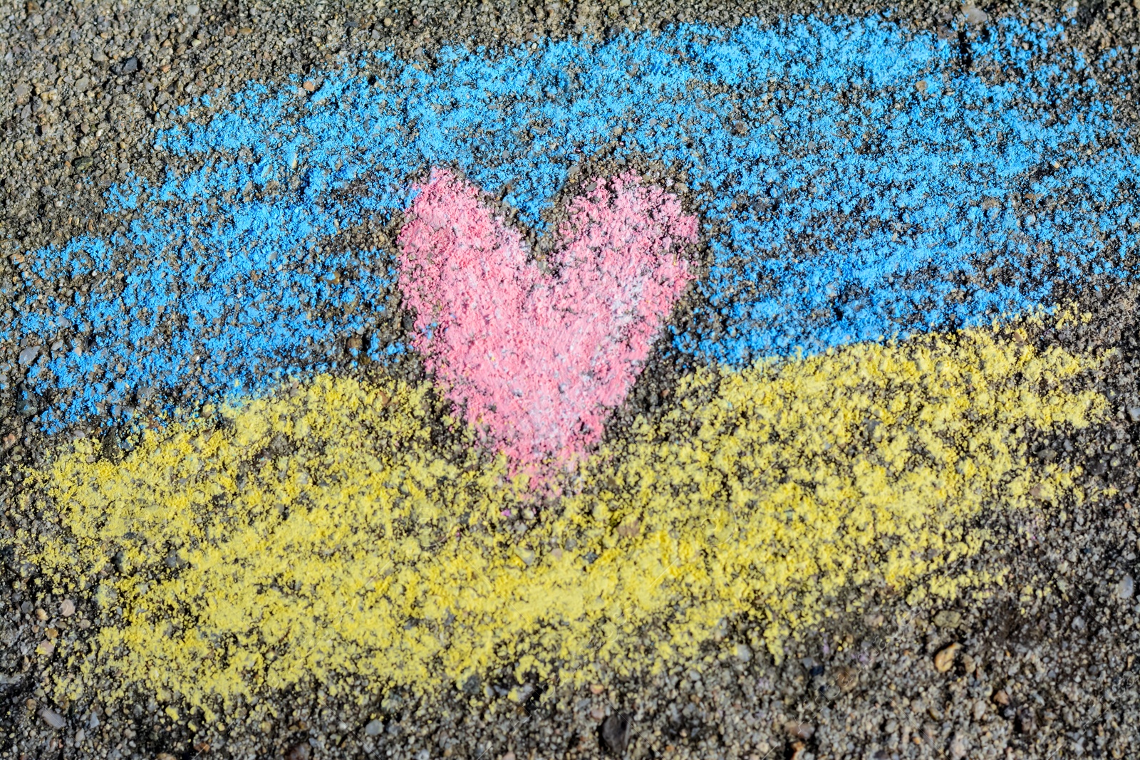 Photo of National flag of Ukraine with heart drawn by color chalk on asphalt, top view