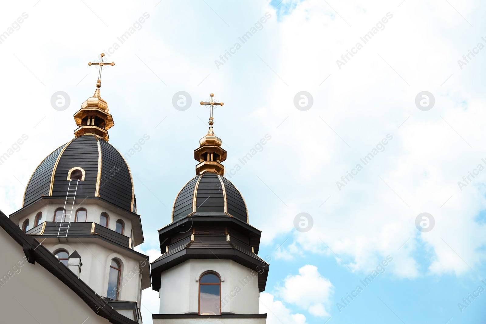 Photo of Beautiful church with golden domes against cloudy sky. Space for text