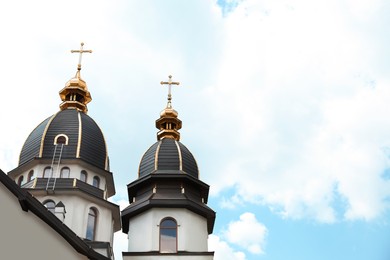 Beautiful church with golden domes against cloudy sky. Space for text