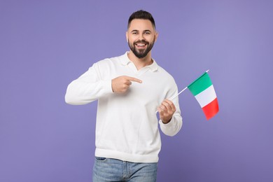 Young man holding flag of Italy on purple background