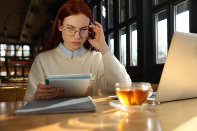 Photo of Young female student with laptop studying at table in cafe