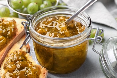 Photo of Jar with delicious gooseberry jam on table, closeup