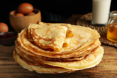 Photo of Stack of fresh thin pancakes on wooden table