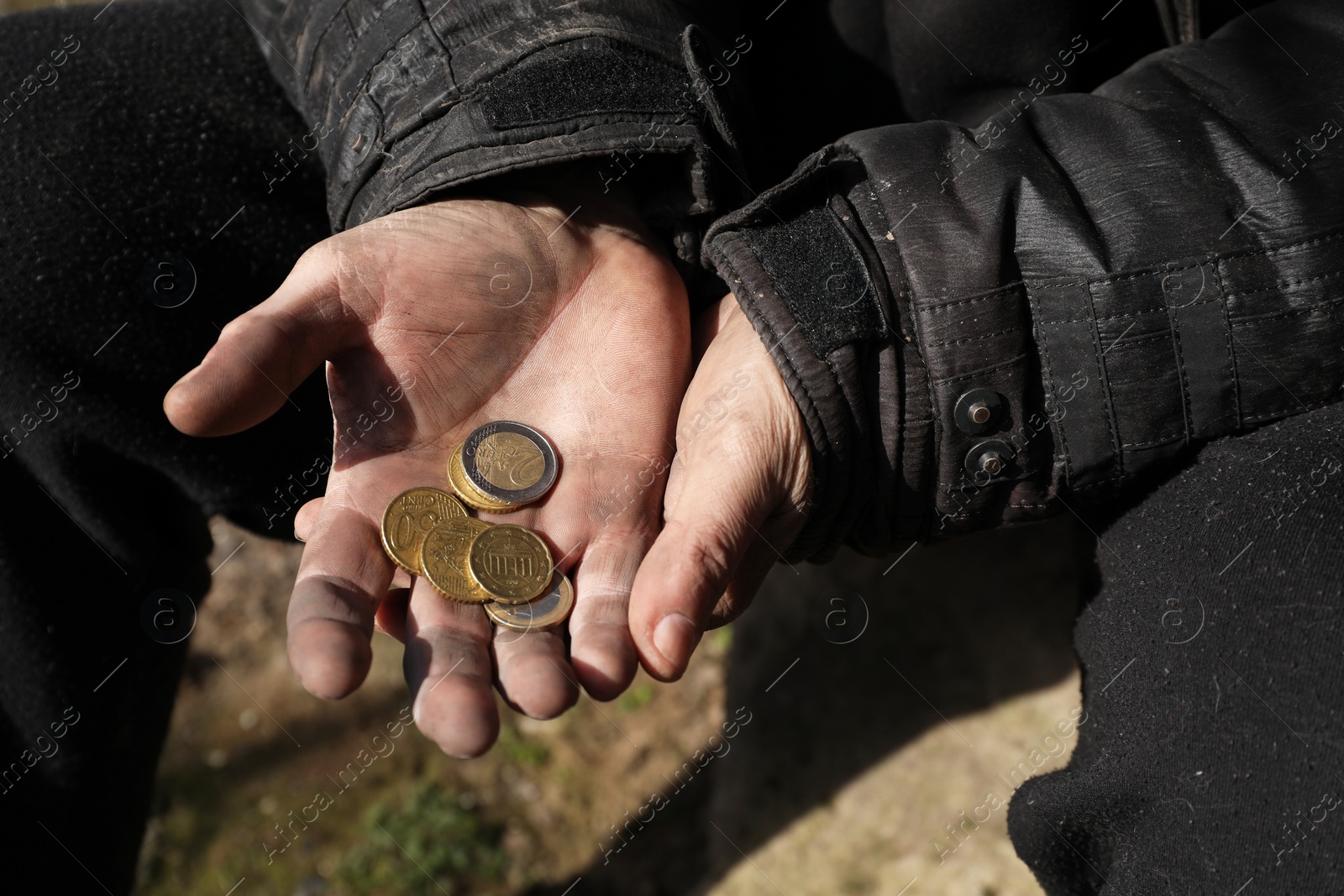 Photo of Poor homeless man holding coins outdoors, closeup