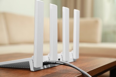 Photo of New modern Wi-Fi router on wooden table indoors, closeup. Space for text