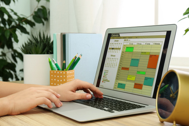 Photo of Woman using calendar app on laptop in office, closeup