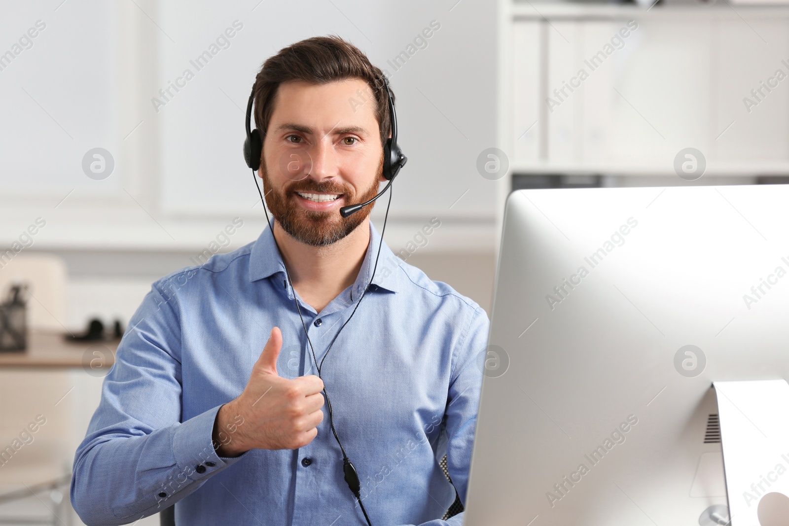 Photo of Hotline operator with headset showing thumbs up in office, space for text