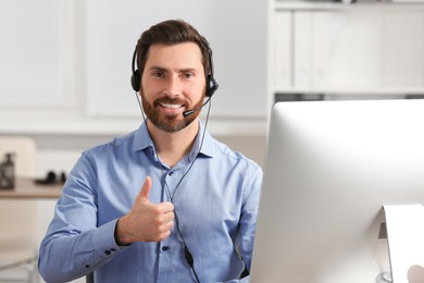 Hotline operator with headset showing thumbs up in office, space for text