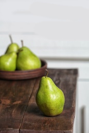 Photo of Ripe pear on wooden table against blurred background. Space for text