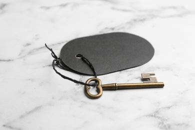 Vintage key with blank tag on white marble table. Keyword concept