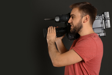 Operator with professional video camera on black background