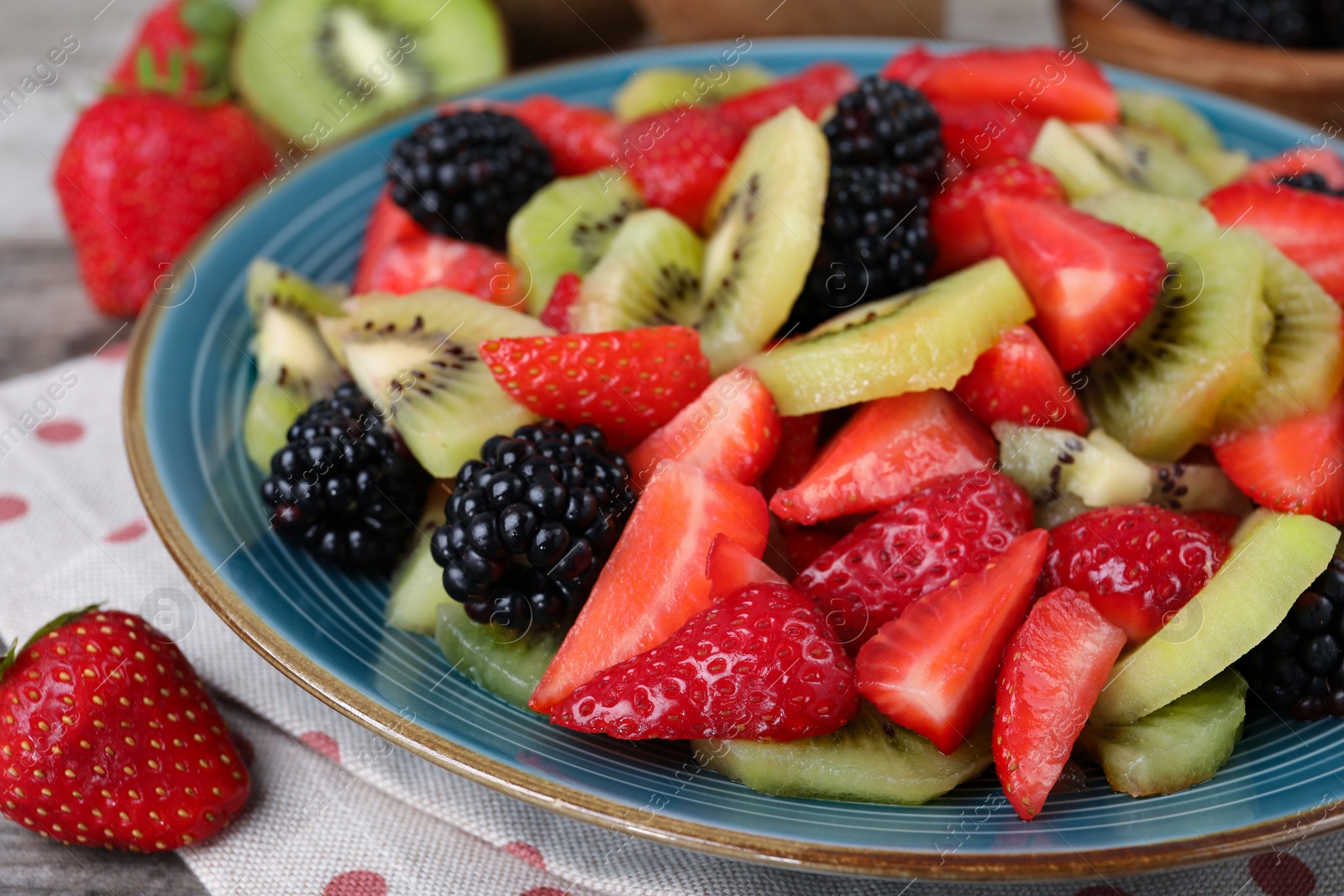 Photo of Plate of delicious fresh fruit salad on table, closeup