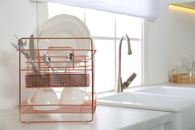 Clean dishes on drying rack in modern kitchen interior