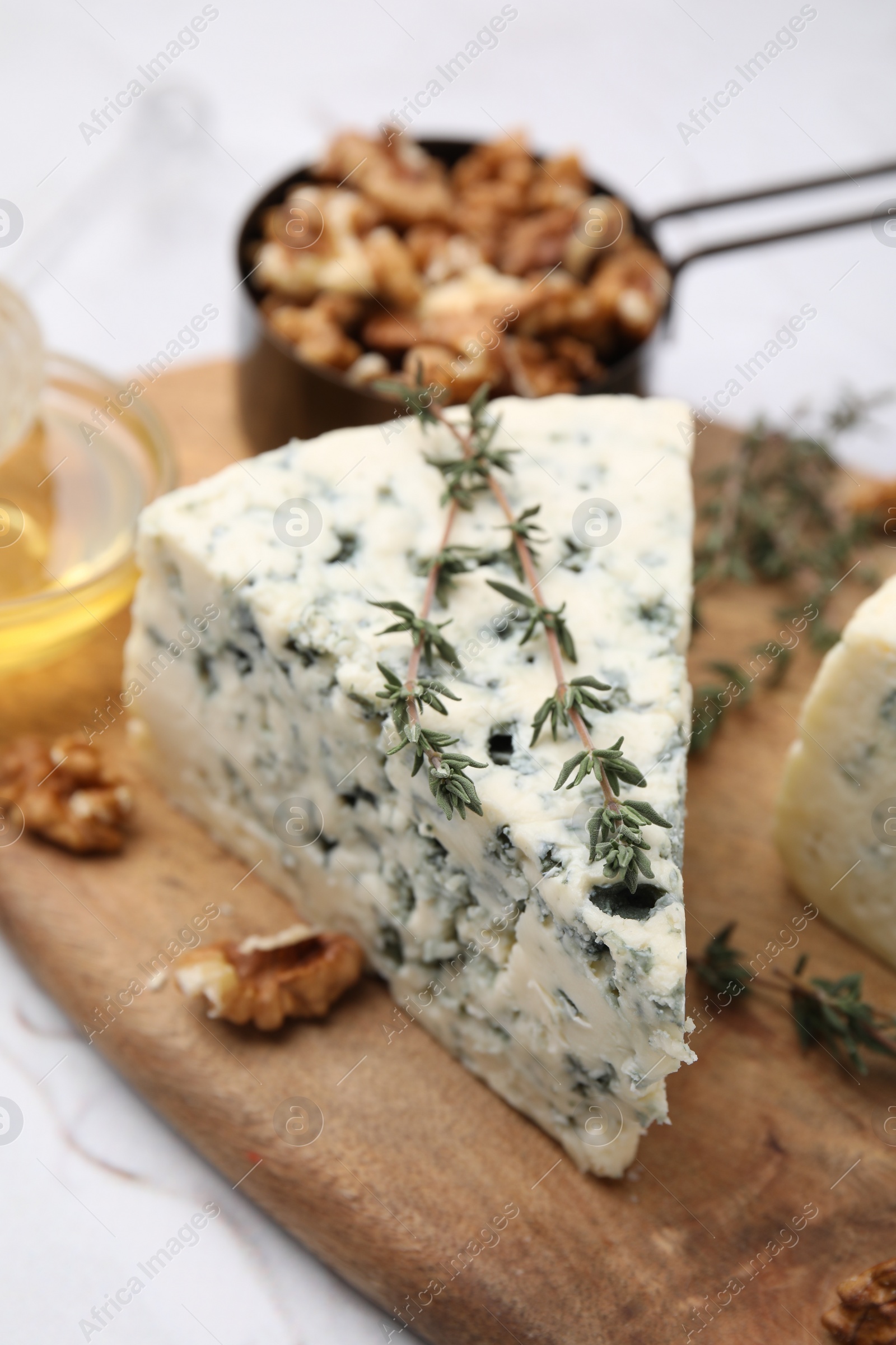 Photo of Tasty blue cheese with thyme, honey and walnuts on white table