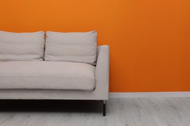 Photo of Comfortable sofa near bright orange wall indoors