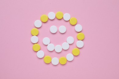 Happy face made of antidepressant pills on pink background, flat lay