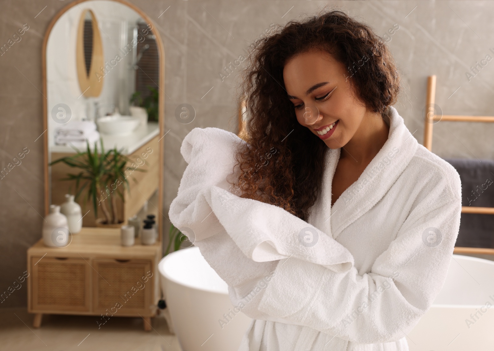 Photo of Beautiful African American woman drying hair with towel in bathroom