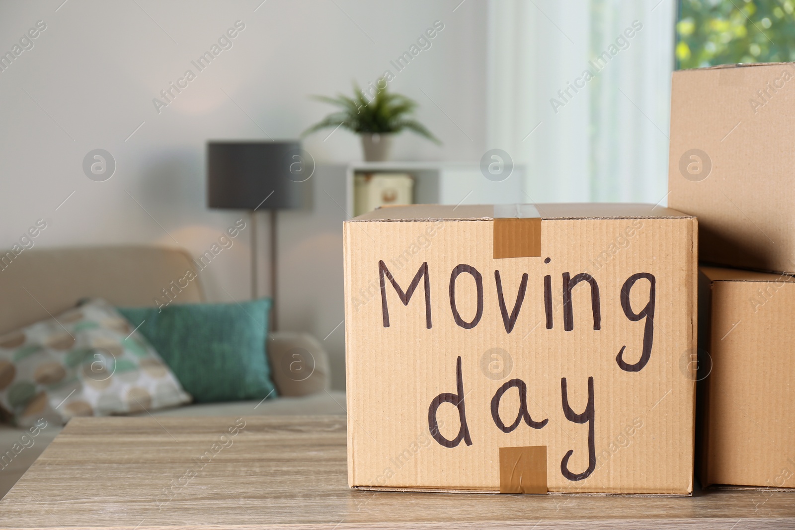 Photo of Cardboard boxes on table against blurred background. Moving day