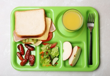 Photo of Serving tray with healthy food on light background, top view. School lunch
